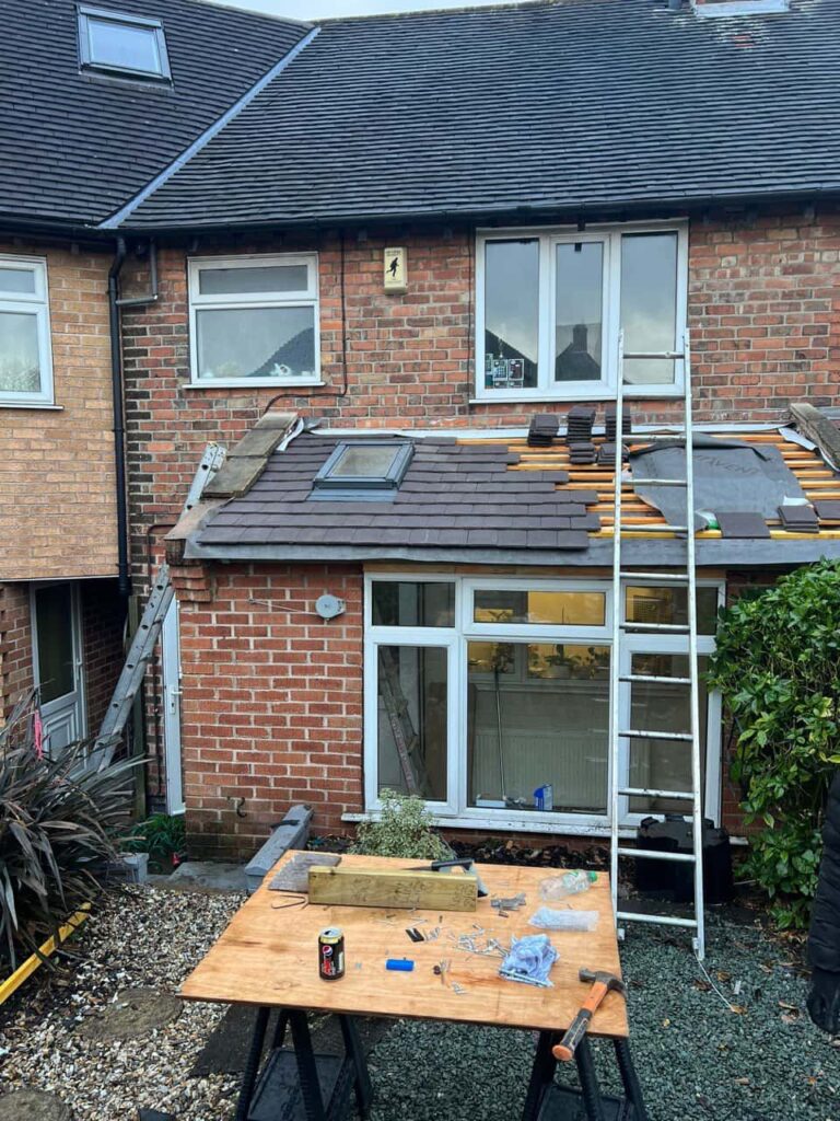 This is a photo of a roof extension that is having new roof tiles installed. This is a photo taken from the roof ridge looking down a tiled pitched roof on to a flat roof. Works carried out by Haywards Heath Roofing Repairs