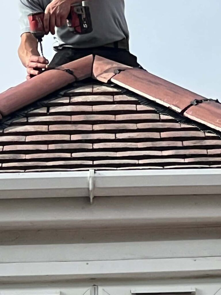 This is a photo of one of the operatives of Haywards Heath Roofing Repairs installing new ridge tiles